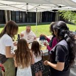 Children and adults gathered around for a seed planting activity
