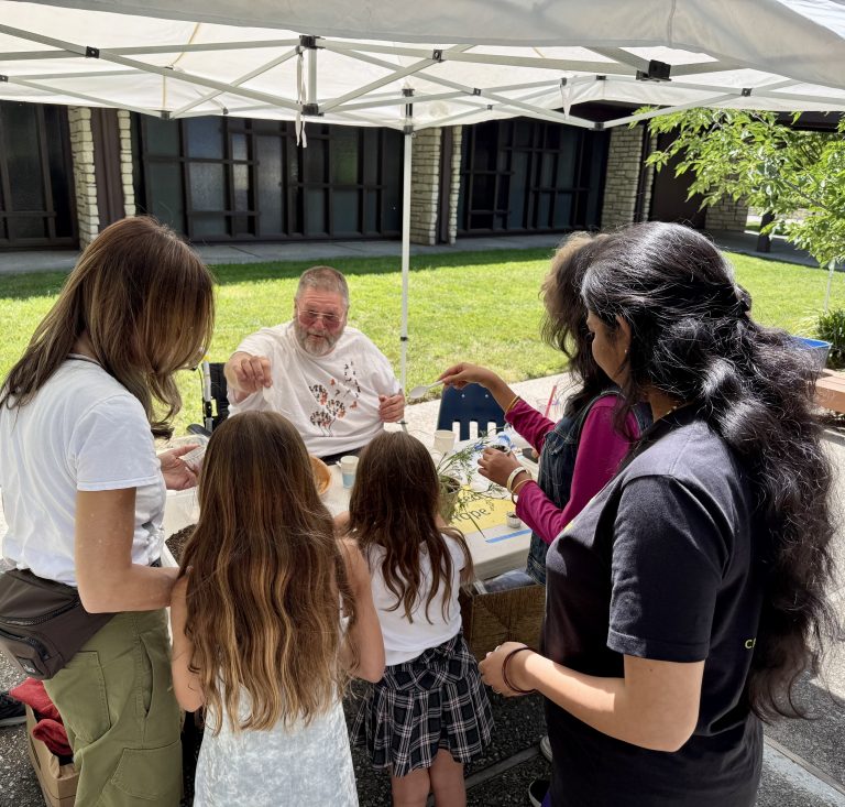 Children and adults gathered around for a seed planting activity