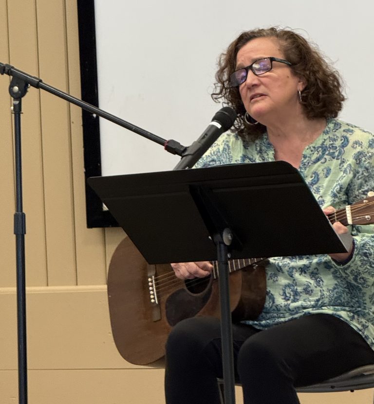 Eve Decker leading the audience in song in the Parish Hall.